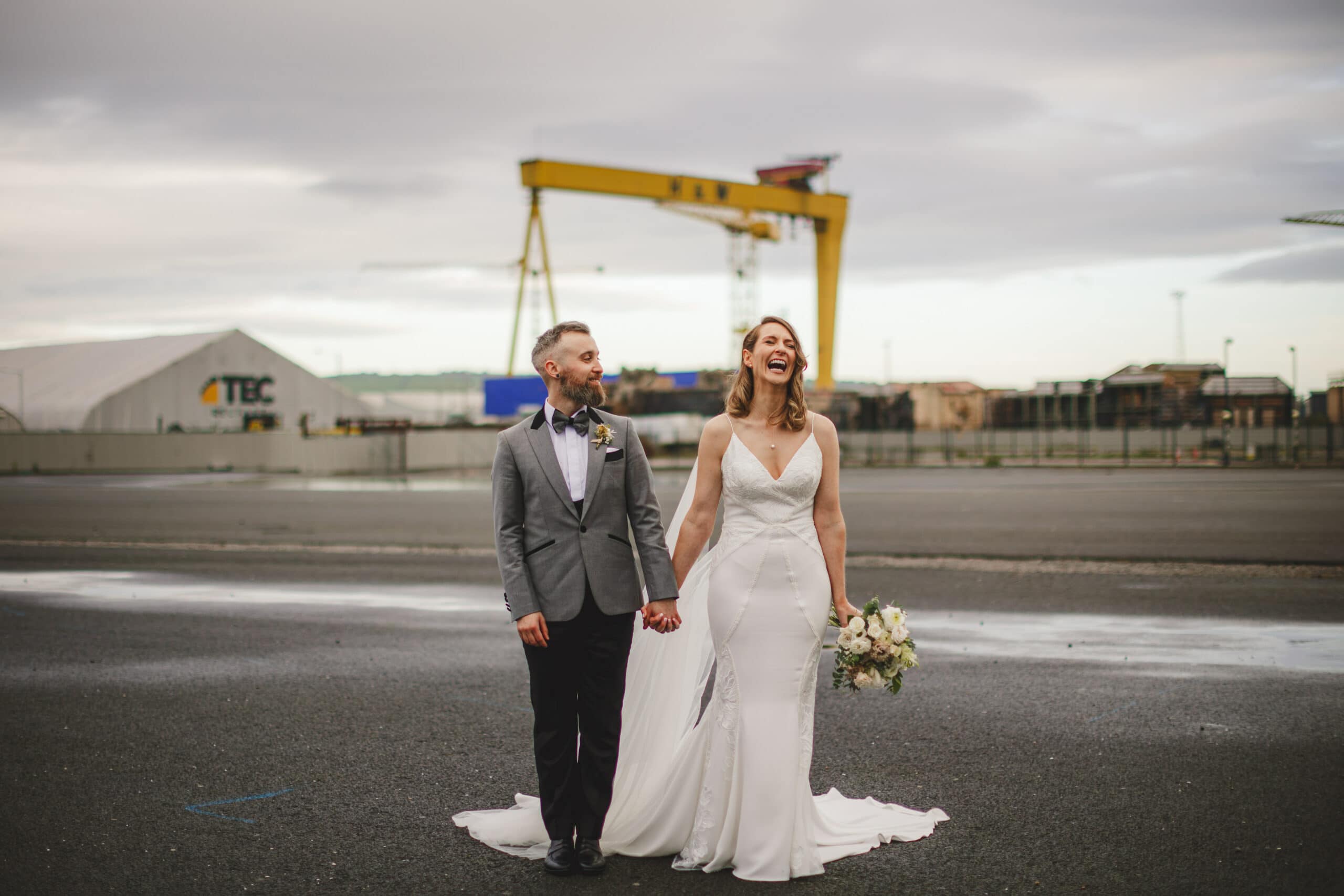 A bride and groom standing in front of of the Harland and Wolff crane in Belfast