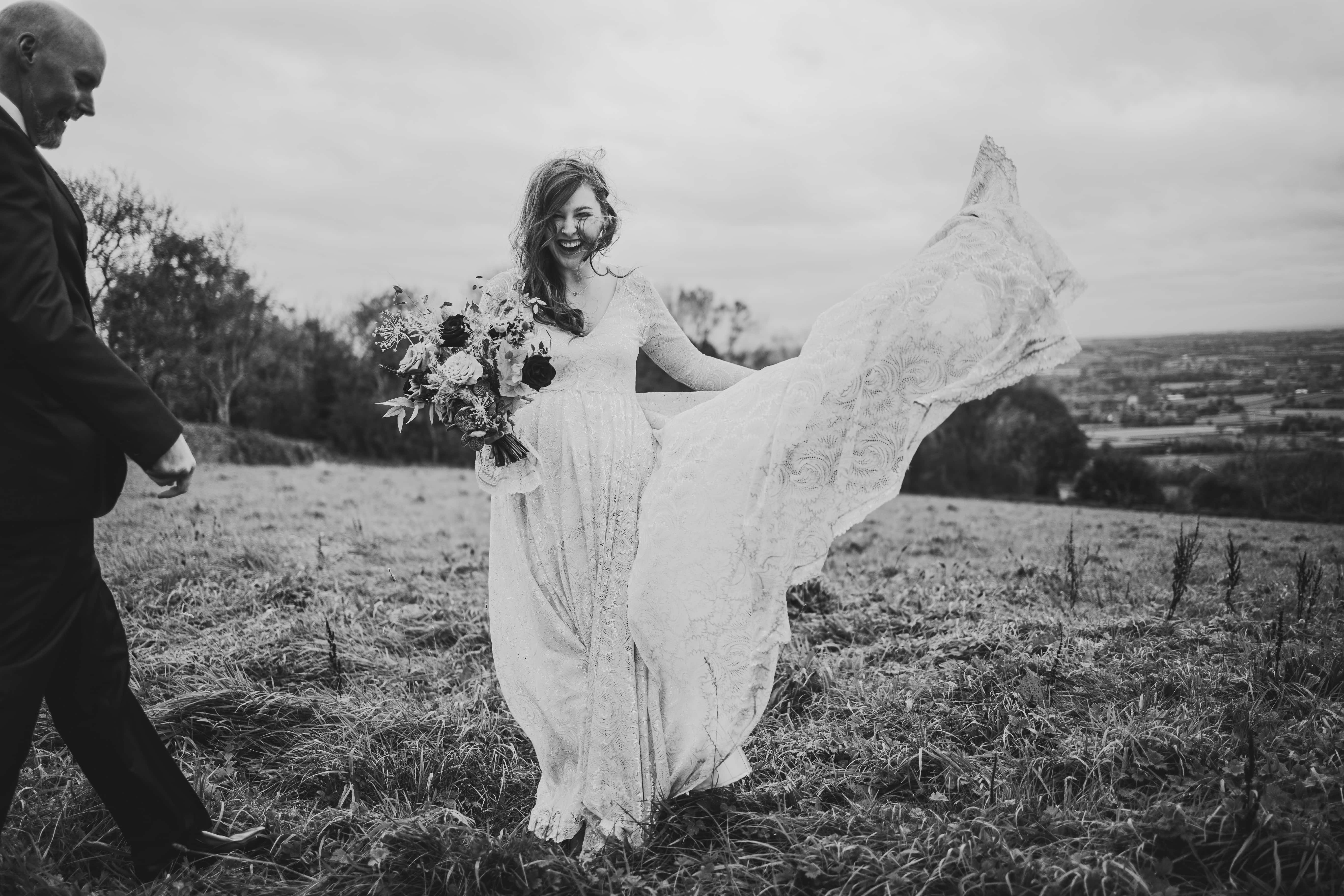 A bride standing in a field in County Antrim with their hair blowing in the wind.