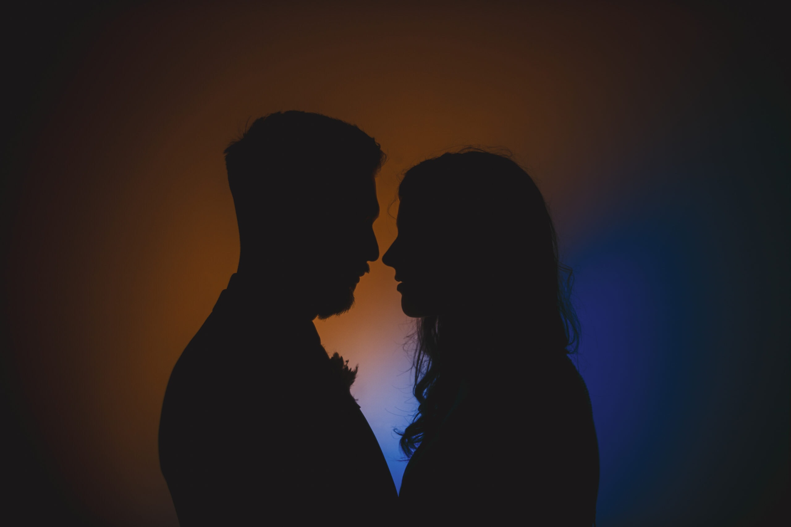 A silhouette of a bride and groom in front of a vibrant background.
