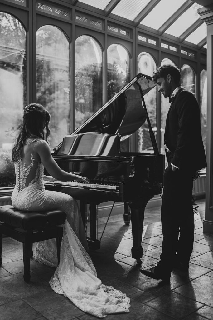 A bride playing the piano and groom standing watching her  at Magheramourne in Northern Ireland.