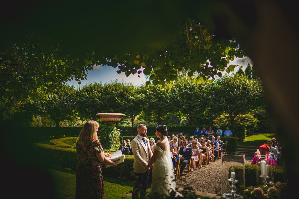 A beautiful wedding ceremony in a charming garden, featuring a bride and  groom on a sunny day at Larchfield