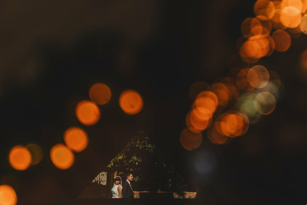 A bride and groom standing in front of bokeh lights at one of the exquisite The Loft